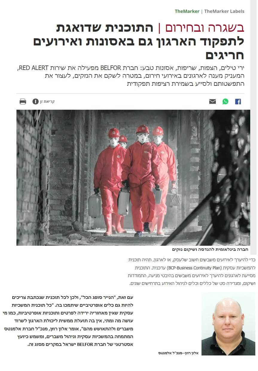 Four people wearing red hazmat suits and helmets walk in a row down an interior corridor, with industrial pipes visible above them. A portrait of a man appears in the lower right corner.